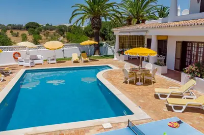 a pool with chairs and umbrellas next to a house at Albufeira Villa El-Gharb private 4 Bedrooms in Albufeira