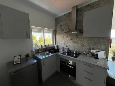 a kitchen with white cabinets and a sink and a window at Ocean view by Charmes C in Albufeira