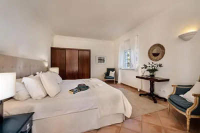 a bedroom with a large white bed and a chair at Dazzling Almancil Villa Villa Magorian 4 Bedrooms Spacious Furnished in Almancil