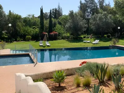 a swimming pool in a yard with chairs and trees at Vilamoura Club Villa 3 With Pool by Homing in Vilamoura