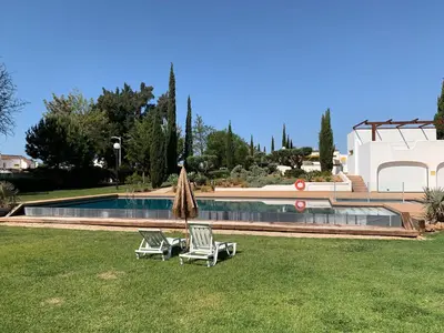 two chairs and an umbrella next to a swimming pool at Vilamoura Club Villa 3 With Pool by Homing in Vilamoura