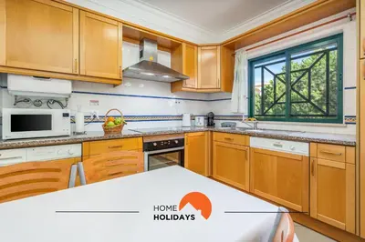 a kitchen with wooden cabinets and a window at #243 Jardins de Santa Eulália H23 by Home Holidays in Albufeira