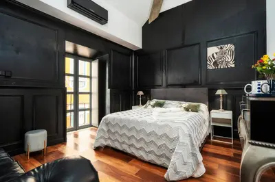 a bedroom with black walls and a bed with a white blanket at Oakmoon House in Faro