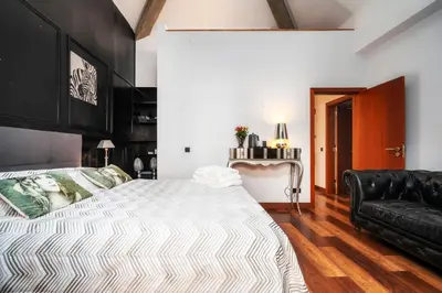 a bedroom with a large bed and a black leather couch at Oakmoon House in Faro