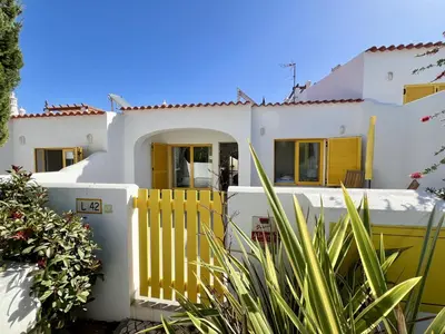 a white house with a yellow fence at Vilamoura Club Villa 2 With Pool by Homing in Vilamoura