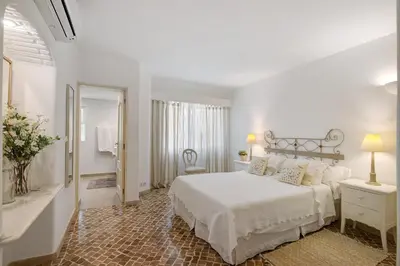 a white bedroom with a bed and a mirror at Casa Isabella in Vilamoura