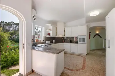 a kitchen with white cabinets and a large window at Casa Isabella in Vilamoura