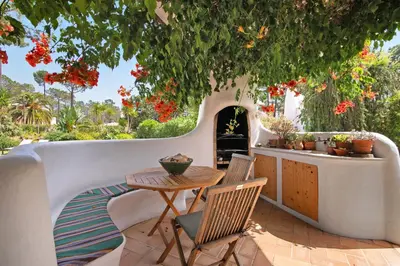 a patio with a table and chairs under a tree at Casa Isabella in Vilamoura