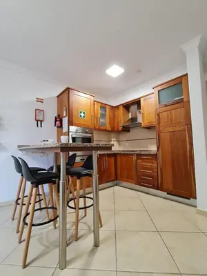 a kitchen with wooden cabinets and a table with bar stools at Colina do Atlântico 203 in Albufeira