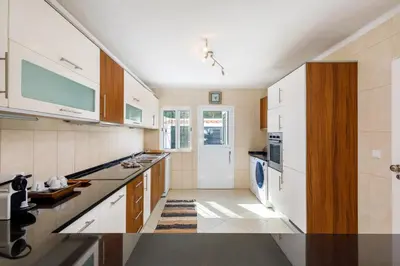 a kitchen with white cabinets and a sink at Villa Carlos in Loulé