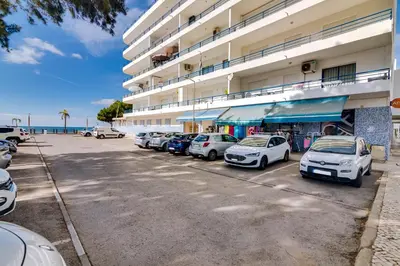 a row of cars parked in a parking lot next to a building at Apartamento Gaivota frente-mar in Quarteira