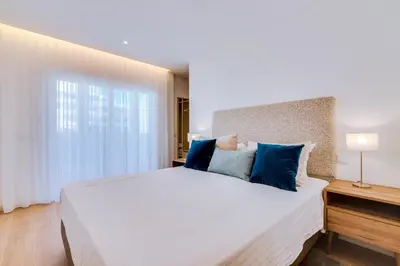 a bedroom with a large white bed with blue pillows at Apartamento Gaivota frente-mar in Quarteira