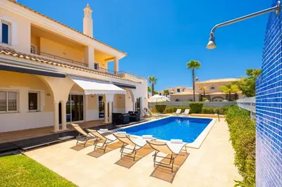 a villa with a swimming pool and chairs at Villa Coute Real in Quarteira