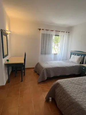 a bedroom with two beds and a desk and a window at Apartamento São Rafael Holidays in Albufeira