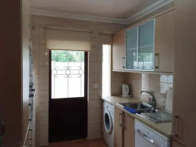 a kitchen with a black door and a washing machine at Apartamento São Rafael Holidays in Albufeira