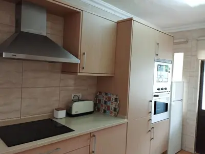 a kitchen with wooden cabinets and a stove top oven at Apartamento São Rafael Holidays in Albufeira