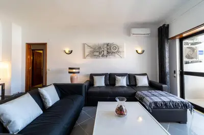 a living room with a black couch and a table at Garnero Apartment by HelloVacations in Albufeira