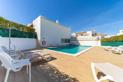 a patio with a pool and chairs and a table at Garnero Apartment by HelloVacations in Albufeira