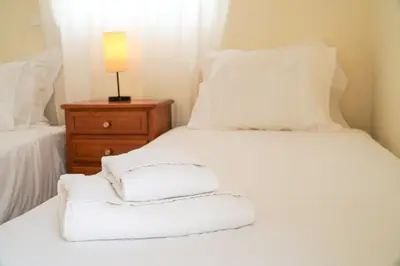 a bed with white sheets and a lamp on a night stand at Villa Lydika I in Albufeira