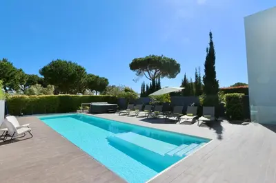 a swimming pool in a yard with chairs and an umbrella at Villa Pinheiro CD 84 - Cleverdetails in Vilamoura