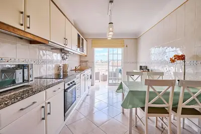 a kitchen with white cabinets and a table and chairs at Apartment O Monte mit Pool in Guia
