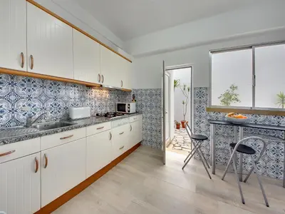 a kitchen with white cabinets and a table with chairs at Inn The Beach Apartments by Seareen in Albufeira