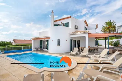 a villa with a swimming pool in front of a house at #245 Quinta do Julo by Home Holidays in Albufeira