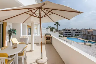 a patio with a table and an umbrella on a balcony at Casa da Praia in Albufeira