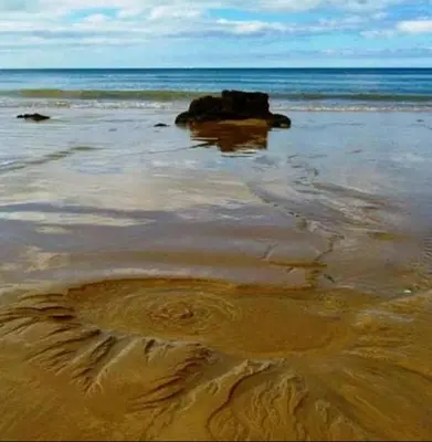 a sandy beach with a rock in the water at Casa da Praia in Albufeira