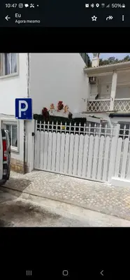 a white fence in front of a house with a parking sign at RECANTO da FELICIDADE in Albufeira