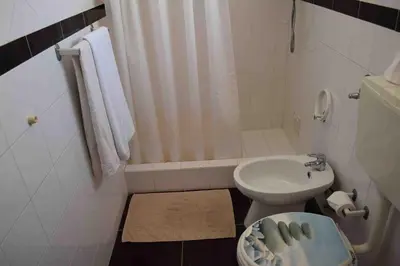 a white bathroom with a toilet and a sink at Villa V4 Filomena in Mosqueira