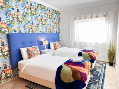 two beds in a bedroom with colorful wallpaper at Golden Palm Condo by BeCherish in Albufeira