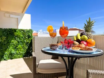 a table with a plate of fruit and wine glasses at Golden Palm Condo by BeCherish in Albufeira