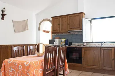a kitchen with wooden cabinets and a table with a table cloth at Monte dos Avós in Querença