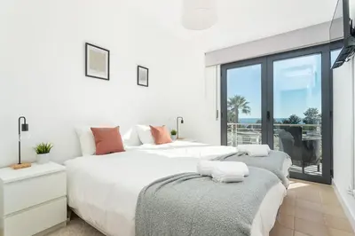 two beds in a bedroom with a view of the ocean at Host Wise - Serene Spacious House - Swimming Pool & Garden in Olhos de Água