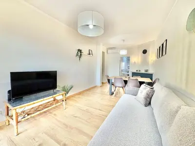 a living room with a couch and a tv at Sea Front 180º View with AC and WiFi in Quarteira