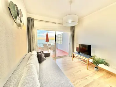 a living room with a couch and a flat screen tv at Sea Front 180º View with AC and WiFi in Quarteira