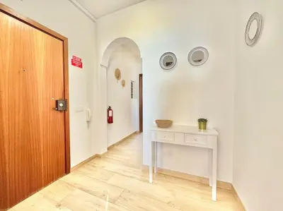 a hallway with a table and a clock on the wall at Direct Beach Access with Sea View, AC & WiFi in Quarteira