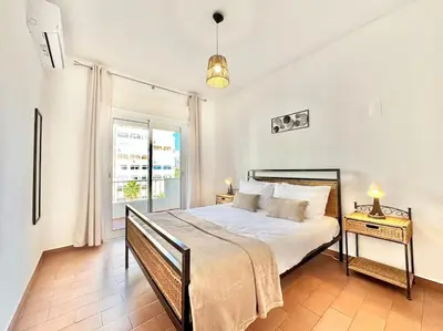 a bedroom with a large bed and a window at Direct Beach Access with Sea View, AC & WiFi in Quarteira
