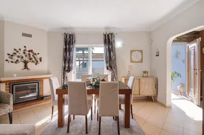 a dining room and living room with a table and chairs at Casa das Buganvilias in Loulé