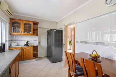 a kitchen with a refrigerator and a table and chairs at Casa das Buganvilias in Loulé