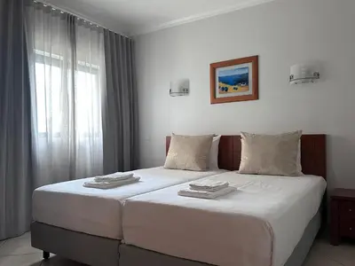 a bedroom with two beds with white sheets and a window at Oceanview Bliss in Albufeira Retreat Over Oldtown in Albufeira