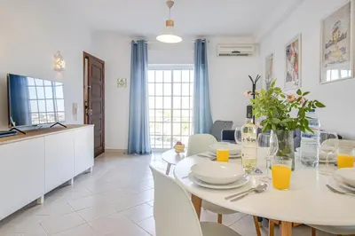 a white dining room with a white table and chairs at Cozy Apt 5min Beach Ocean View AC Wi Fi in Albufeira