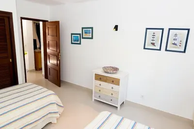 a white bedroom with a bed and a dresser at The Albufeira Concierge - Villa Praia São Rafael in Albufeira