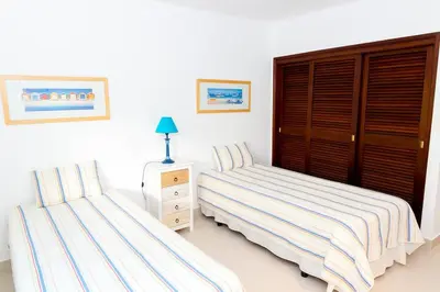 a bedroom with two beds and a dresser with a night stand at The Albufeira Concierge - Villa Praia São Rafael in Albufeira