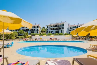 a swimming pool with chairs and umbrellas at 2 bedroom apt Vila Sol in Quarteira