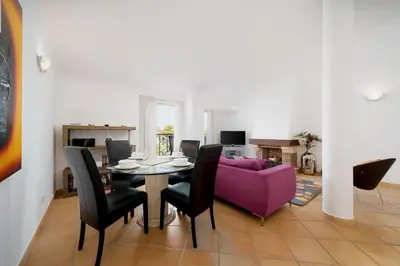 a dining room with a table and a purple couch at 2 bedroom apt Vila Sol in Quarteira