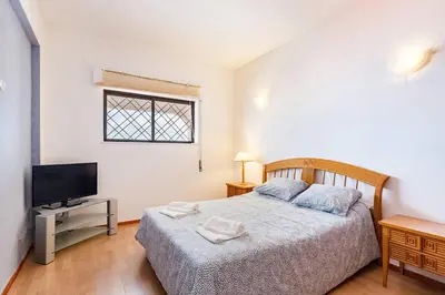a bedroom with a bed and a flat screen tv at TAC - Sunrise Montechoro Albufeira in Albufeira