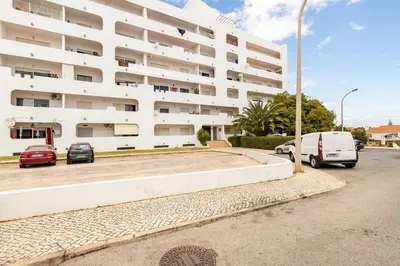 a white building with cars parked in a parking lot at TAC - Sunrise Montechoro Albufeira in Albufeira