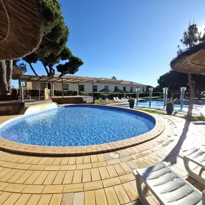 a swimming pool with two chairs and an umbrella at Moradia V2 - 200m da Praia da Oura - Santa Eulália in Albufeira